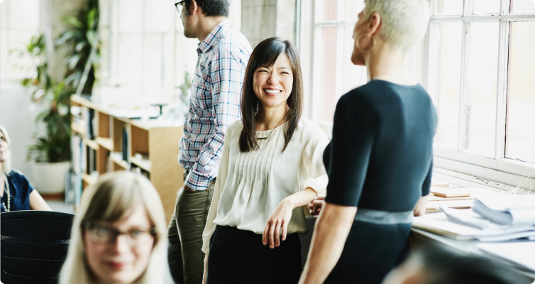 Two women have a discussion while standing in an office