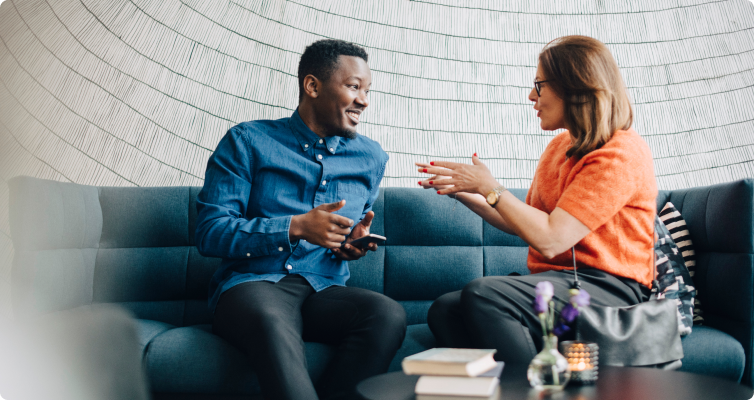 A man and woman have a discussion while sitting on a sofa