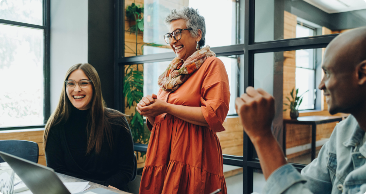 Three colleagues laugh in a team meeting