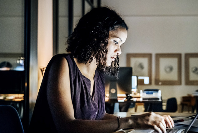 Woman works on her laptop at desk late at night